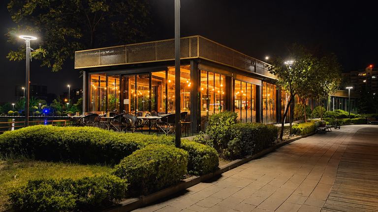 Göksu Katre Cafe & Bistro'nun gece ışıklı cam cephesi ve park yürüyüş yolu